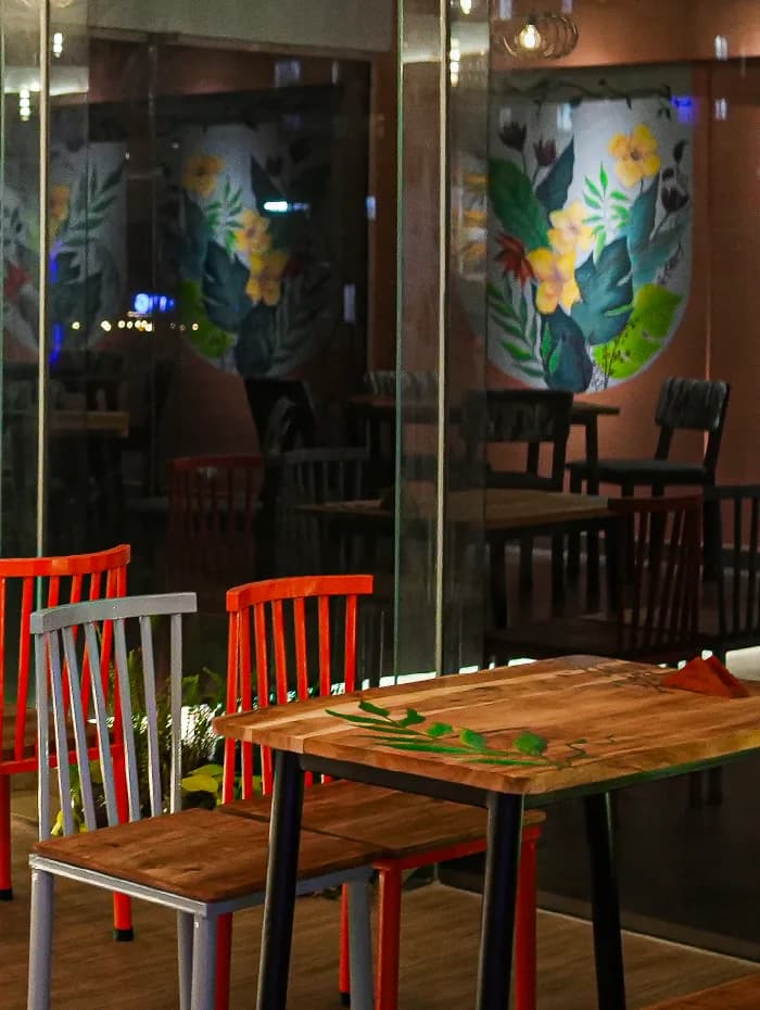 Tropical mural painted across the glass partition, with the dining room beyond