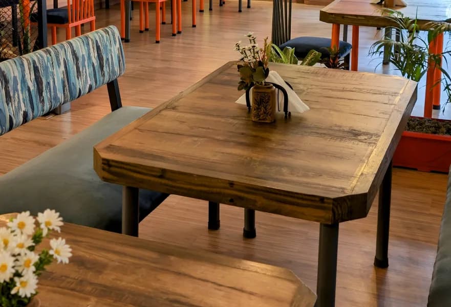 Solid timber tables and grey banquette seating, set with daisies