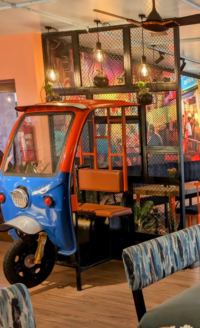 The blue tuk-tuk booth under caged pendant lamps, beside patterned banquette seating