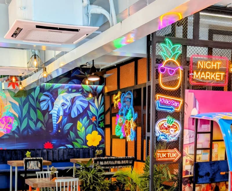 The neon signage wall and jungle mural seen past the pendant lighting rig